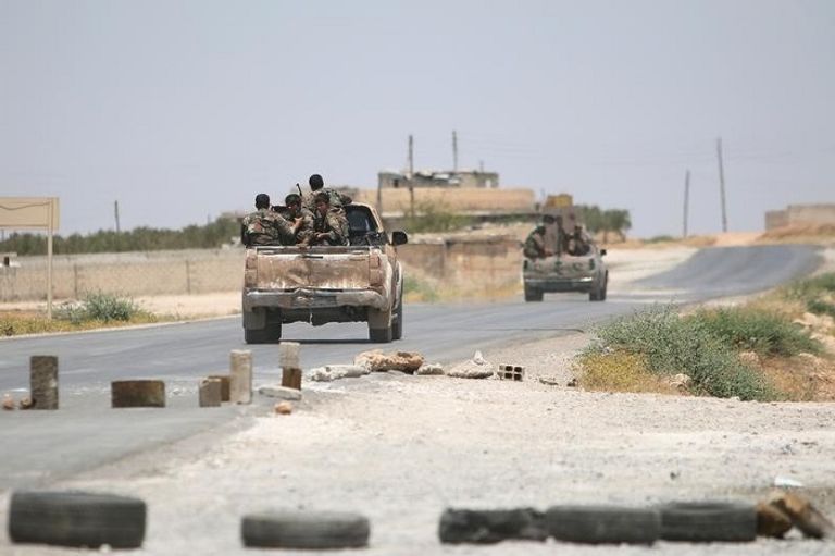 صورة أرشيفية لعناصر من قوات سوريا الديمقراطية على طريق بالقرب من منبج (رويترز)