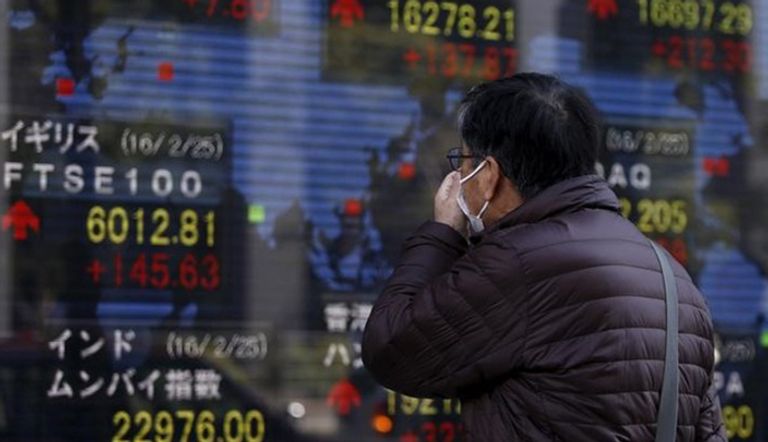 رجل يمر بلوحة تعرض مؤشرات الأسواق الآسيوية في طوكيو 