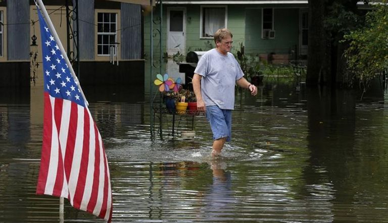 رجل يسير وسط المياه في منطقة غمرتها السيول