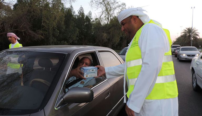 أحد عناصر الشرطة يوزع وجبات الإفطار على السائقين وقت المغرب