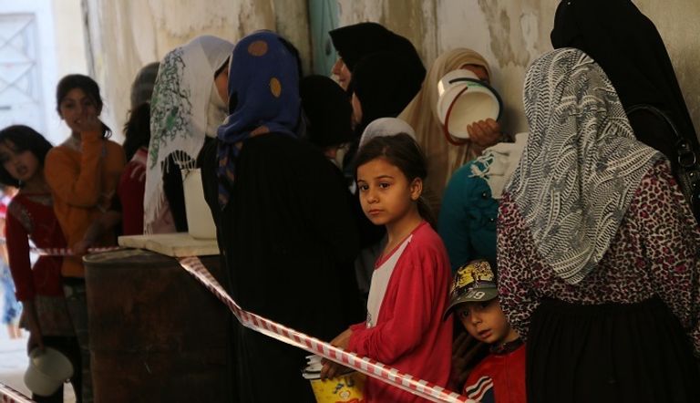 سوريون يقفون في طابور بانتظار الحصول على وجبات إفطار من جمعية خيرية