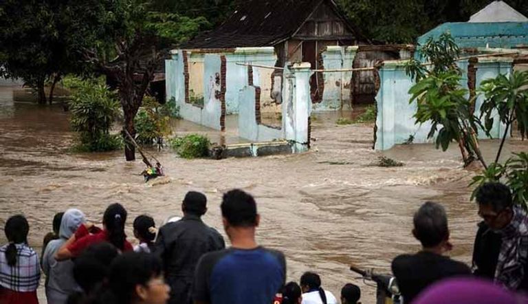 أشخاص يقفون أمام منطقة تغمرها مياه السيول في سولو بجاوة الوسطى