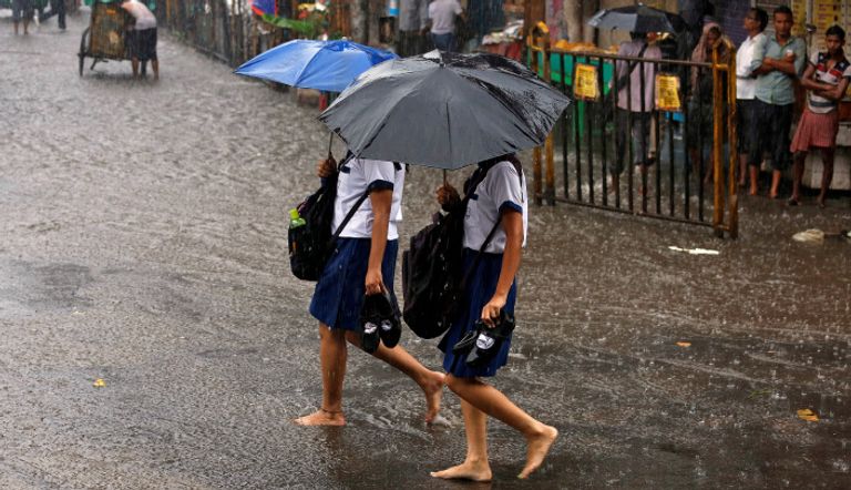 طالبتان ترفعان المظلات وتخلعان الأحذية لمواجهة الأمطار في كولكاتا