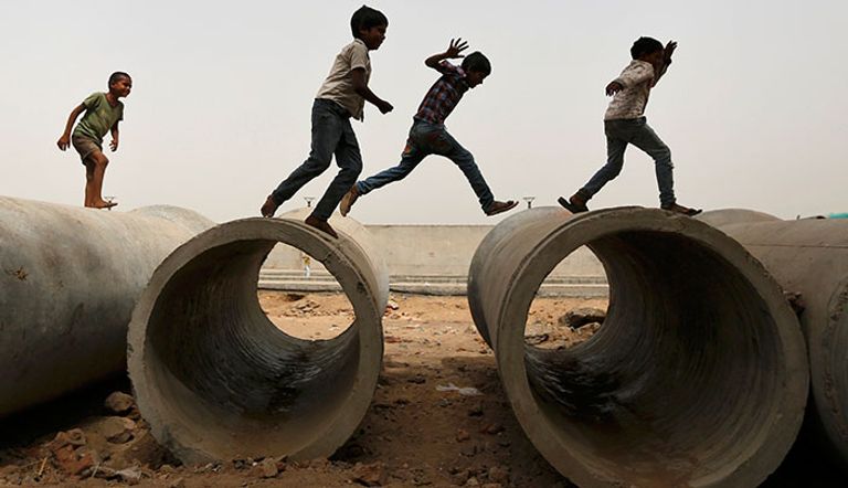 اطفال يلعبون فوق مواسير بموقع بناء في أحمد آباد بالهند