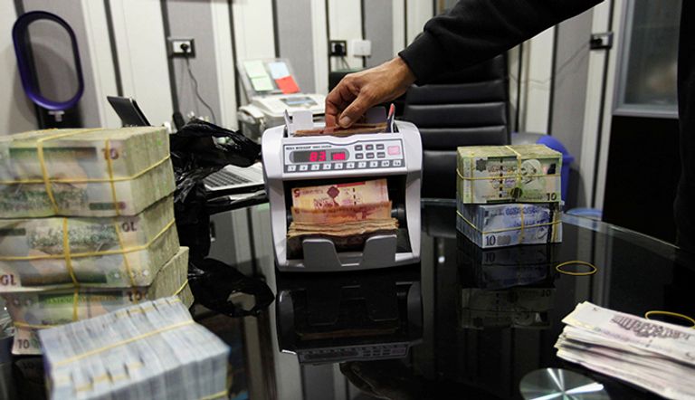 موظف يستخدم آلة عد العملة لحساب دينار ليبي في مكتب صرف العملات في طرابلس