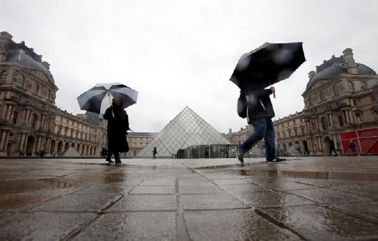 سائحان يسيران قرب متحف اللوفر في باريس