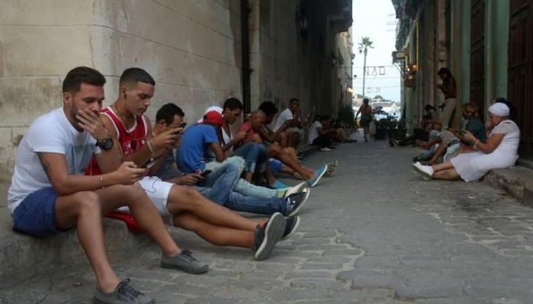 أشخاص يستخدمون هواتفهم المحمولة للدخول إلى شبكة الإنترنت في هافانا