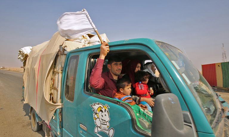 رجل عراقي يلوح بعلم أبيض يجلس مع عائلته نازحا من جنوب الموصل مقاتلون من البيشمركة الكردية على قمة جبل زارداك شرق الموصل