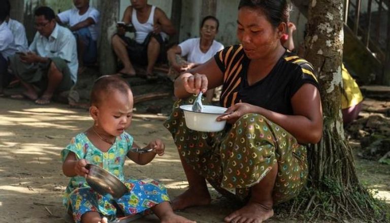 امرأة من عرقية الروهينجا فرت من أحداث العنف في ماونجدو تطعم ابنتها في مأوى مؤقت للمشردين في سيتوي بميانمار
