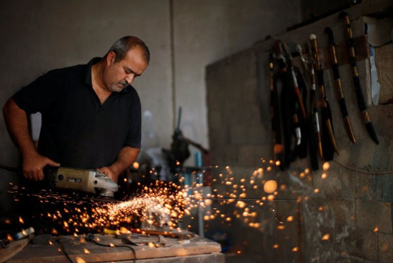 معين أبو وادي يفحص أبعاد أحد السيوف (رويترز)