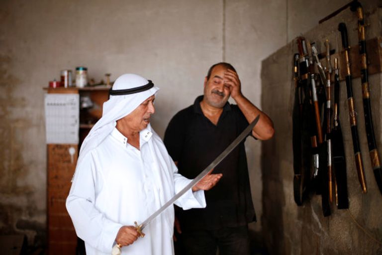 معين أبو وادي يفحص أبعاد أحد السيوف (رويترز)