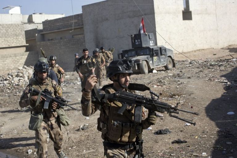 جنود القوات العراقية يحملون جثة امرأة قتلها تنظيم داعش بالموصل