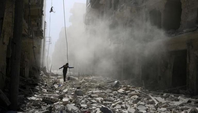 سوري في حلب يسير وسط ركام مباني 