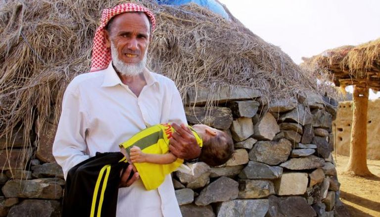 يمني يحمل طفله المريض