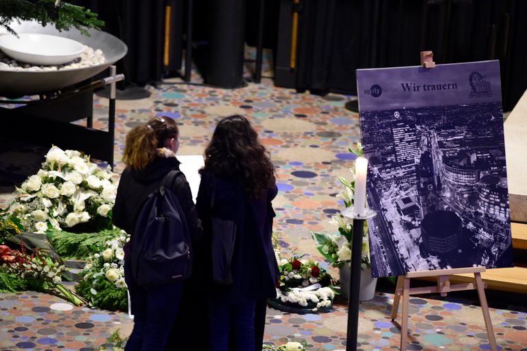 رجل يقف أمام شموع في موقع حادث برلين