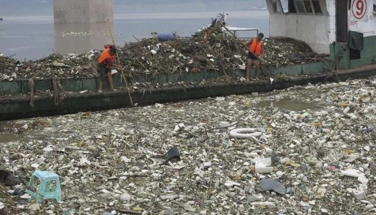 عاملان يجمعان القمامة على زورق في نهر يانغتسي