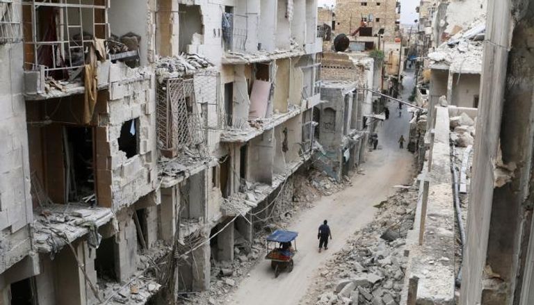 سوريون يسيرون وسط منازل مهدمة في حلب