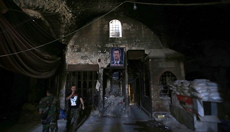 صورة للرئيس السوري بشار الأسد في سوق خان الوزير التي تضررت في الجانب الذي تسيطر عليه الحكومة من مركز مدينة حلب التاريخي القلعة المدرجة في قائمة اليونسكو  في الجانب الذي تسيطر عليه الحكومة في حلب الشمالية