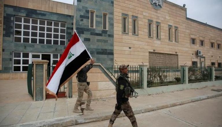 جندي عراقي يحمل علم بلاده في الموصل