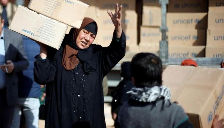 امرأة من النازحين تحمل مساعدات في مخيم للنازحين شمال الموصل