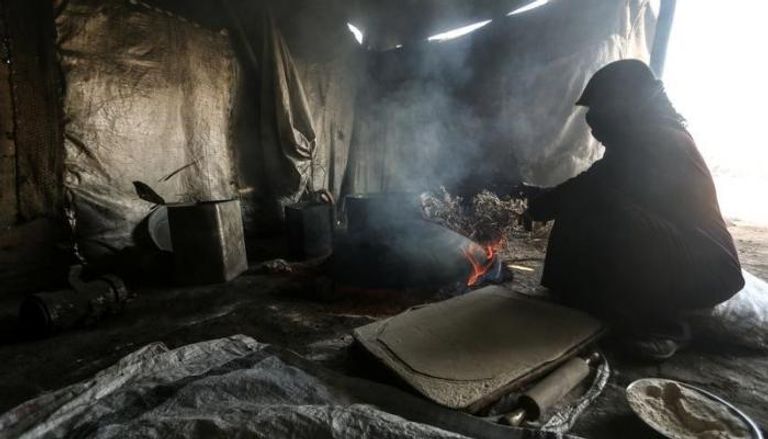سيدة سورية نازحه تعد الطعام في خيمة بمخيم في رأس العين