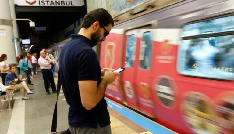 شاب يتسخدم هاتفه الذكي في محطة مترو