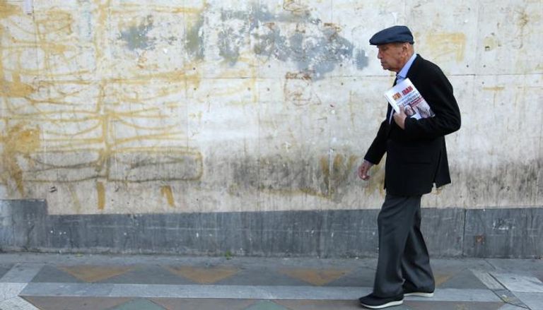 مسن إيراني يحمل الصحف بالعاصمة طهران
