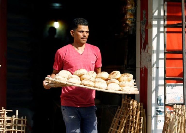 مزارع مصري يحمل سنابل قمح - رويترز