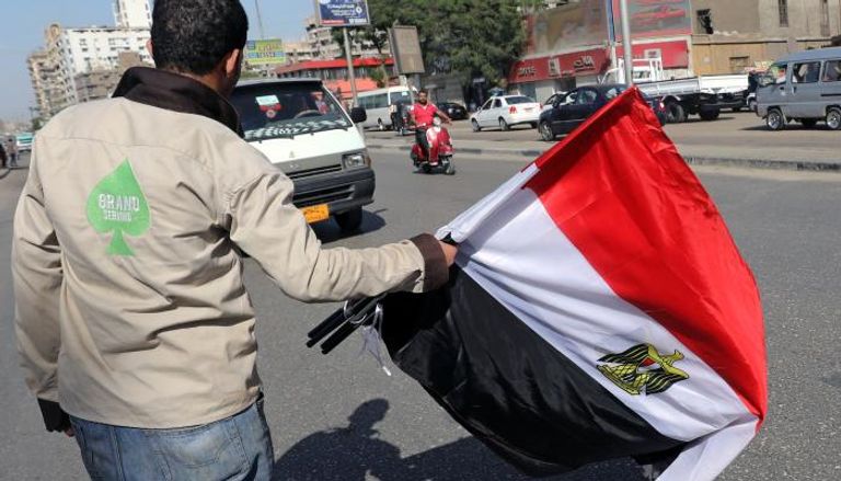 شاب مصري يحمل علم بلاده في أحد شوارع القاهرة (رويترز)