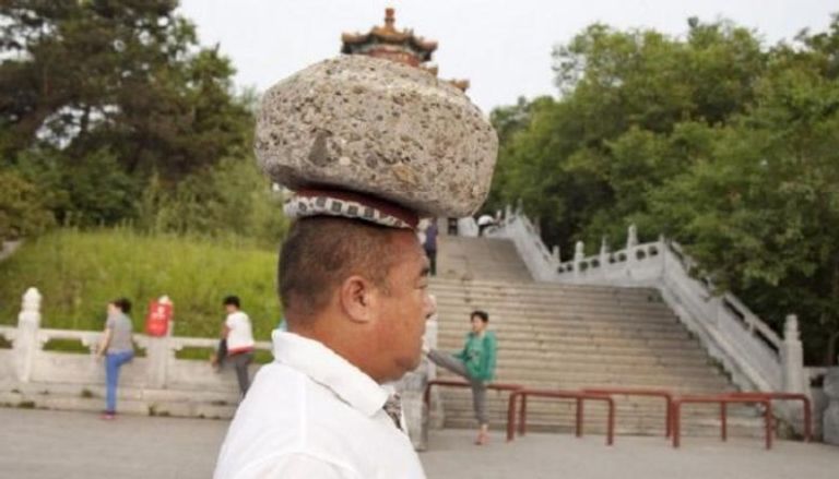 بالفيديو.. لإنقاص وزنه.. صيني يضع على رأسه صخرة تزن 40 كم يوميا