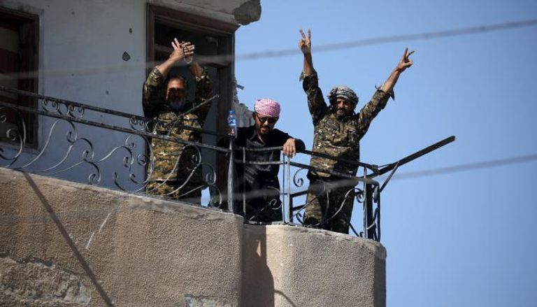قوات سوريا الديمقراطية تشير بعلامات النصر في الرقة