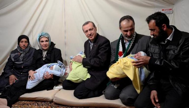 الرئيس التركي خلال زيارته الأطفال الثلاثة عند ولادتهم بمخيم للاجئين