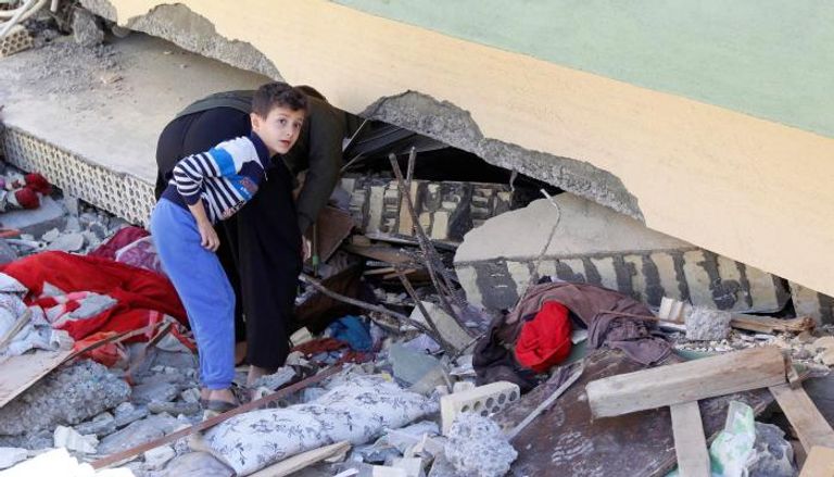 أحد الناجين يبحث عن مقتنياته داخل منزل منهار بعد زلزال إيران (رويترز)