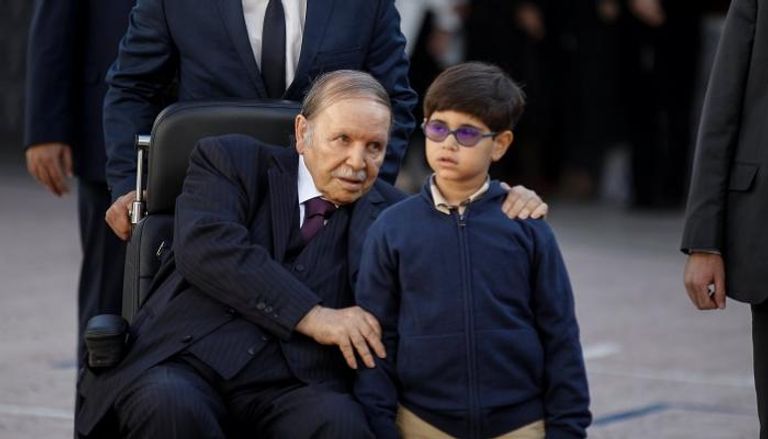 الرئيس الجزائري إلى جانب طفل خلال إدلائه بصوته في الانتخابات - أ. ف. ب