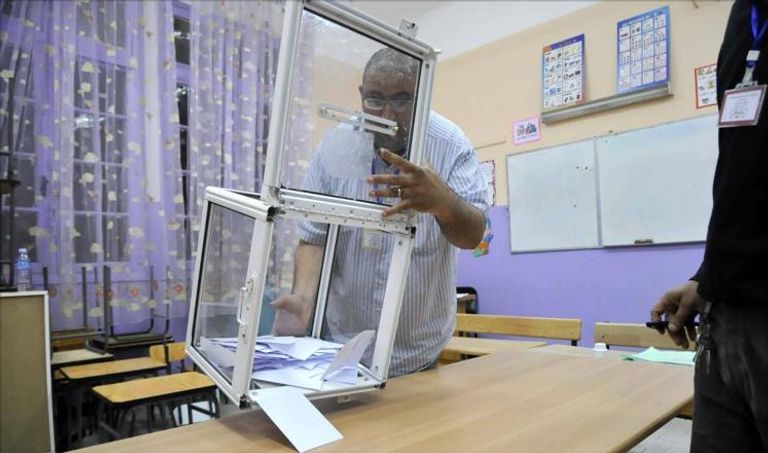 الرئيس الجزائري إلى جانب طفل خلال إدلائه بصوته في الانتخابات - أ. ف. ب