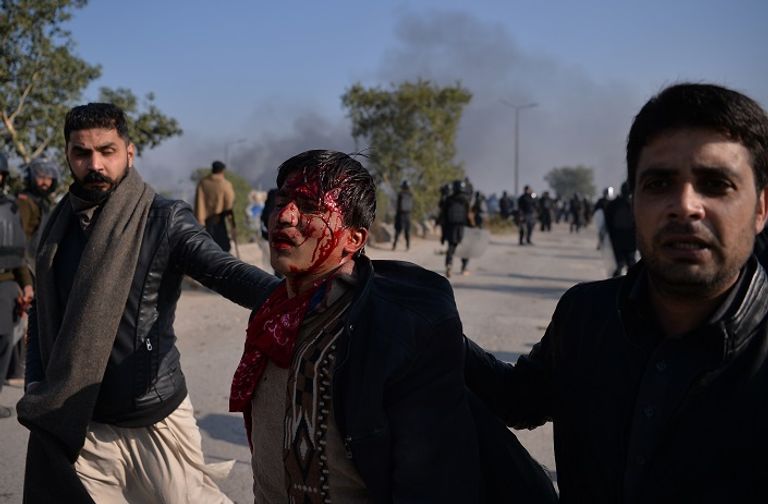 موظف إسعاف يحمل أحد المصابين في الاشتباكات  - أ. ف. ب