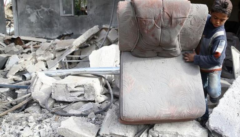 طفل سوري يبحث عن بقايا أثاث منزله تحت الحطام - رويترز