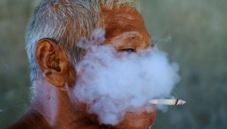 أحد العاملين يدخن سيجارة في جاكارتا-إندونيسيا (رويترز)
