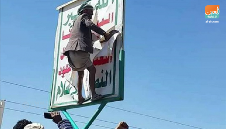 صورة حصرية لـ"بوابة العين" لمواطن يمني يمزق لافتة للحوثيين