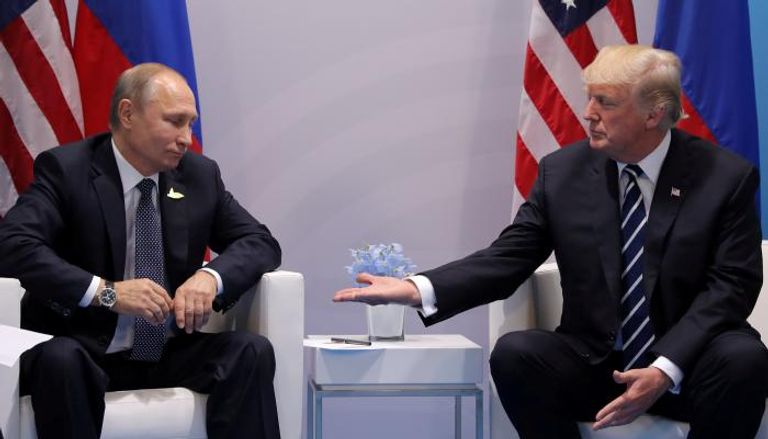 الرئيس الروسي بوتين ينظر إلى يد الرئيس الأمريكي ترامب- (رويترز)