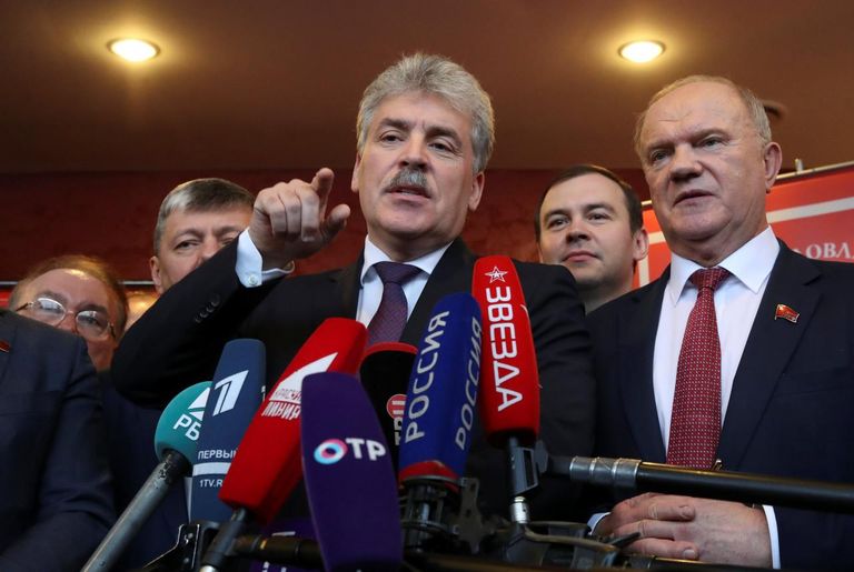 بافيل جرودينين يتحدث للإعلام وبجانبه زعيم الحزب الشيوعي الروسي المخضرم جينادي زيجانوف الرئيس الروسي فلاديمير بوتين ومرشح الحزب الشيوعي بافيل جرودينين