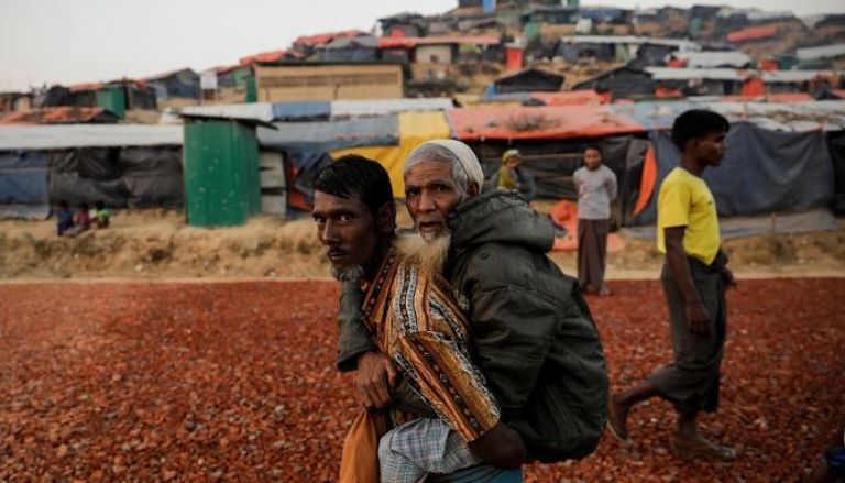لاجئ من الروهينجا يحمل مسن في معكسر ببنجلاديش- رويترز 