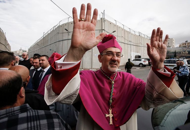 البطريرك بييرباتيستا في القدس، يلوح للمصلين لدى وصوله عبر حاجز إسرائيلي لحضور احتفالات عيد الميلاد- الفرنسية 