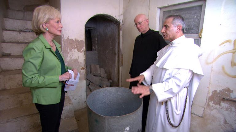 الأب "نجيب ميخائيل" خلال عرضه لأحد الكتب المتضررة