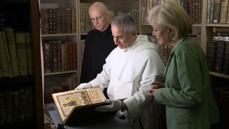 الأب "نجيب ميخائيل" خلال عرضه لأحد الكتب المتضررة