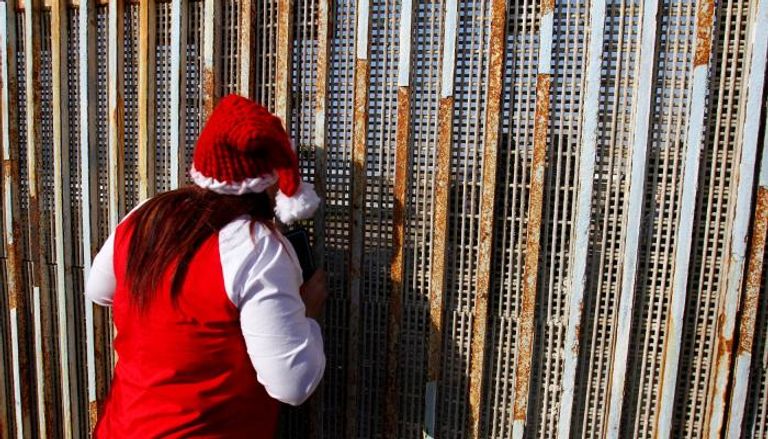 مكسيكية تتحدث لأحد أقاربها عبر الجدار  (رويترز)