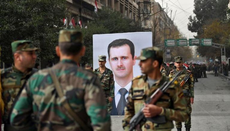 جنود سوريون يقفون بجانب صورة لبشار الأسد (الفرنسية)