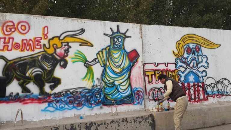 الفنان العراقي أركان البهادلي أمام الجدارية