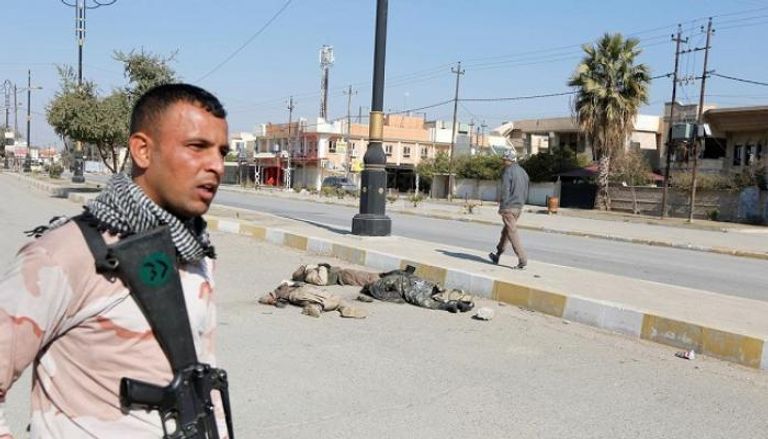 جندي عراقي يقف على مقربة من جثث الدواعش 