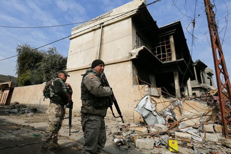 جندي عراقي يقف على مقربة من جثث الدواعش